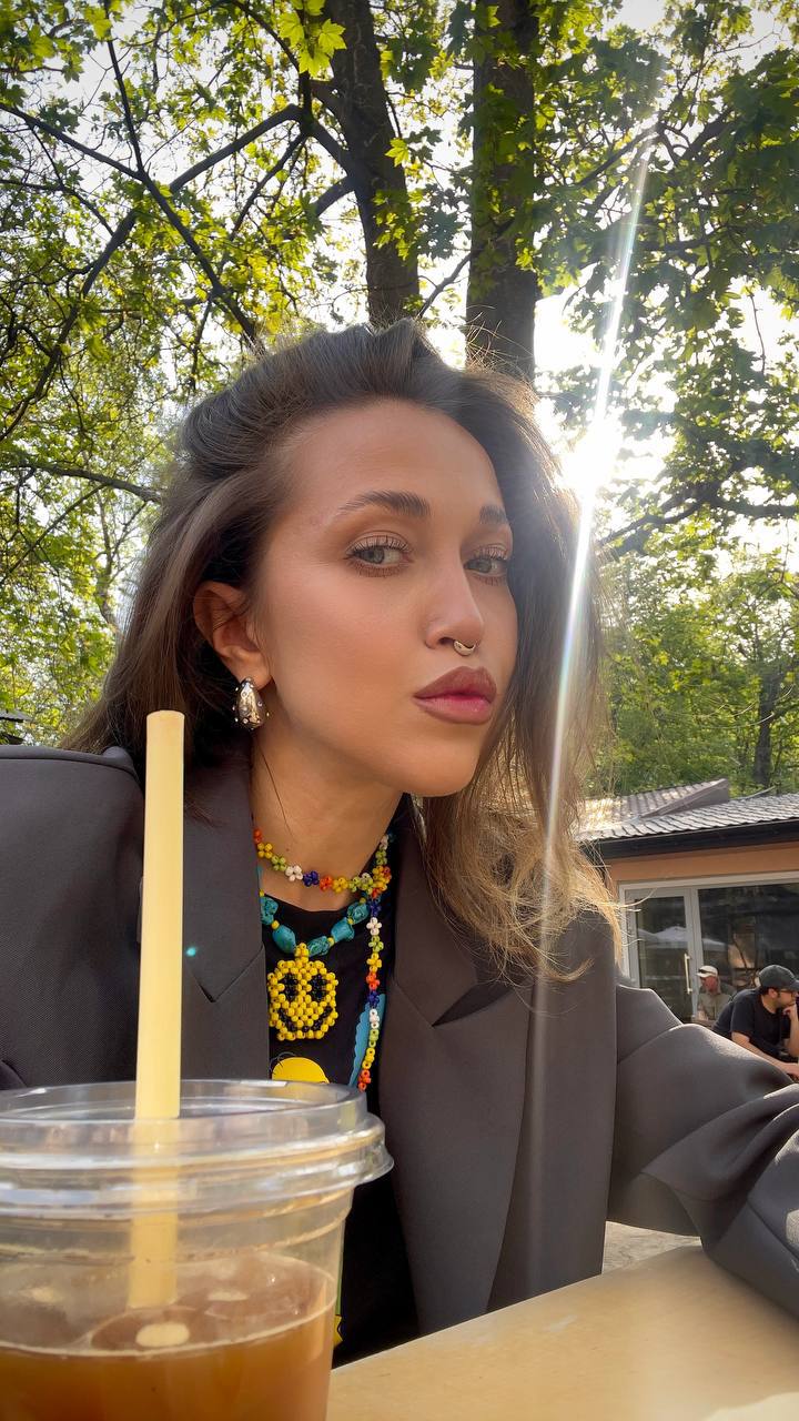 Natali Raievska at outdoor café — grey blazer, iced coffee