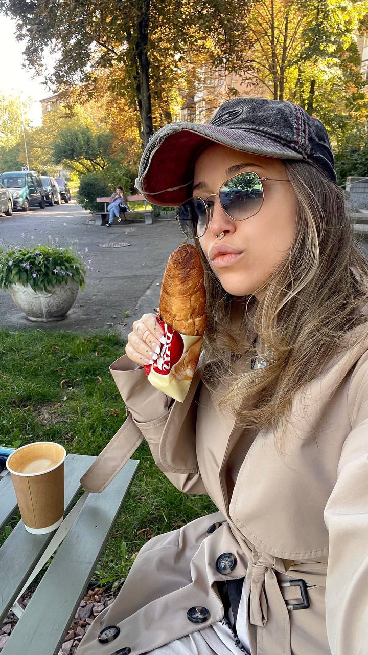 Natali Raievska at park bench with croissant and coffee