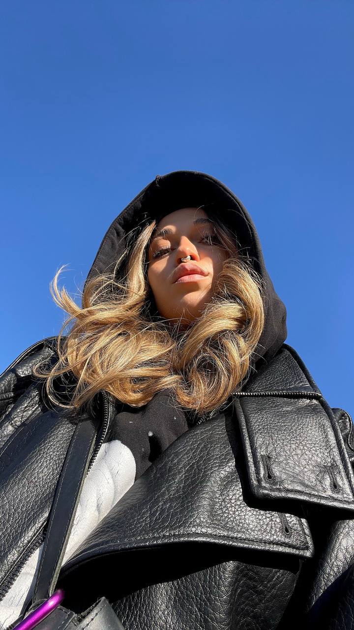 Natali Raievska outdoors — black leather jacket, blue sky